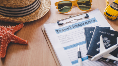 photo of a sign stating travel insurance and several objects depicting travel